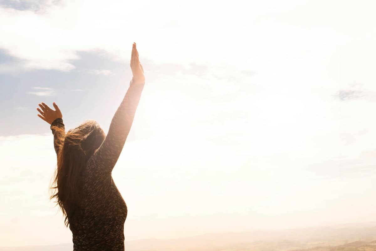 Person with arms lifted toward bright sky, representing hope, renewal, and positive transformation through psychotherapy in New York.