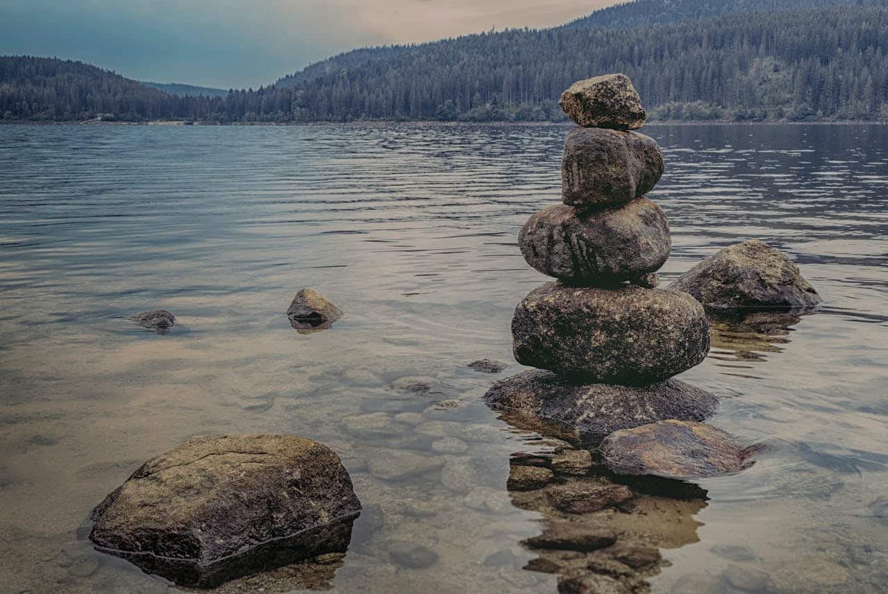 Stack of balanced rocks by a calm lake symbolizing stability and mindful medication management
