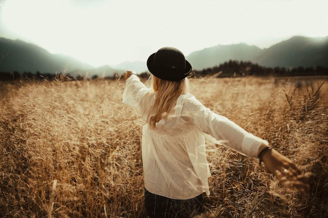 Woman standing in an open field with arms outstretched, symbolizing freedom, stability, and emotional balance during bipolar disorder recovery